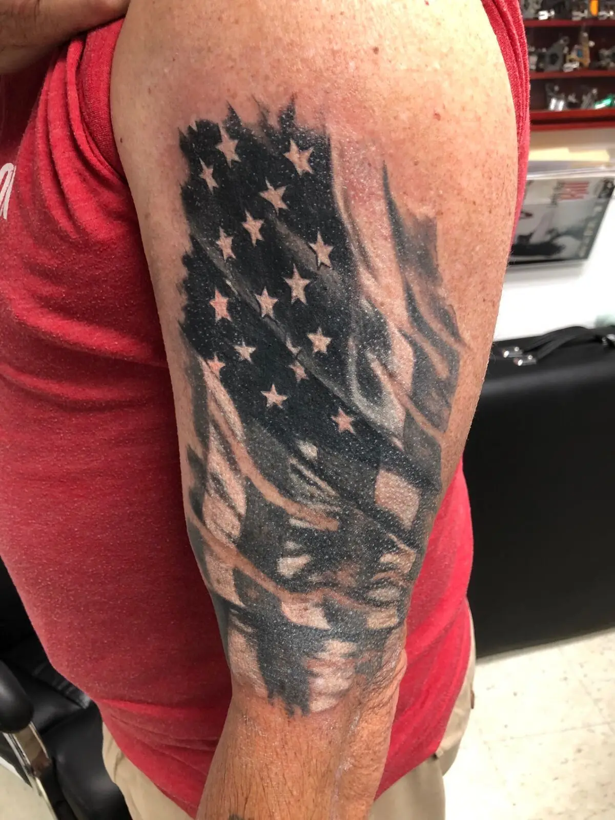 Black and grey American flag tattoo flowing down the upper arm