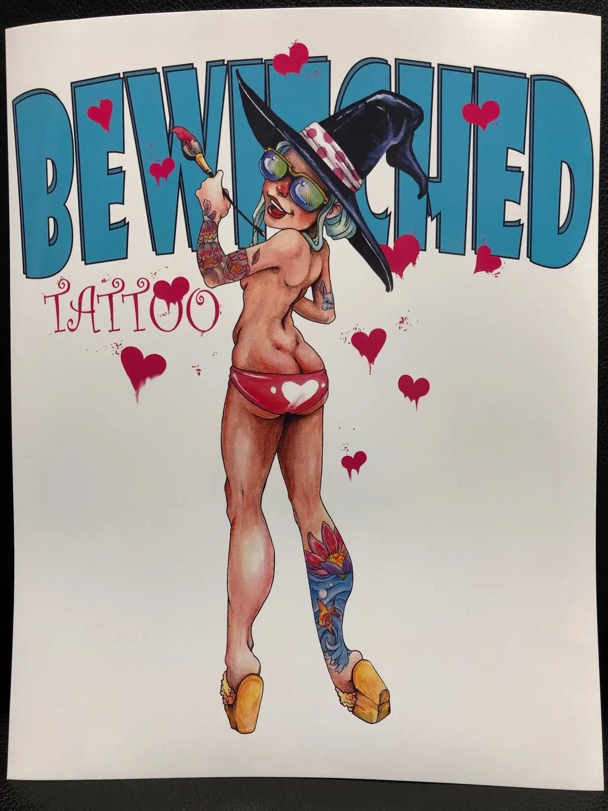 Bewitched Tattoo poster illustration of a tattooed witch pinup in a wide-brim hat holding a paintbrush, by John