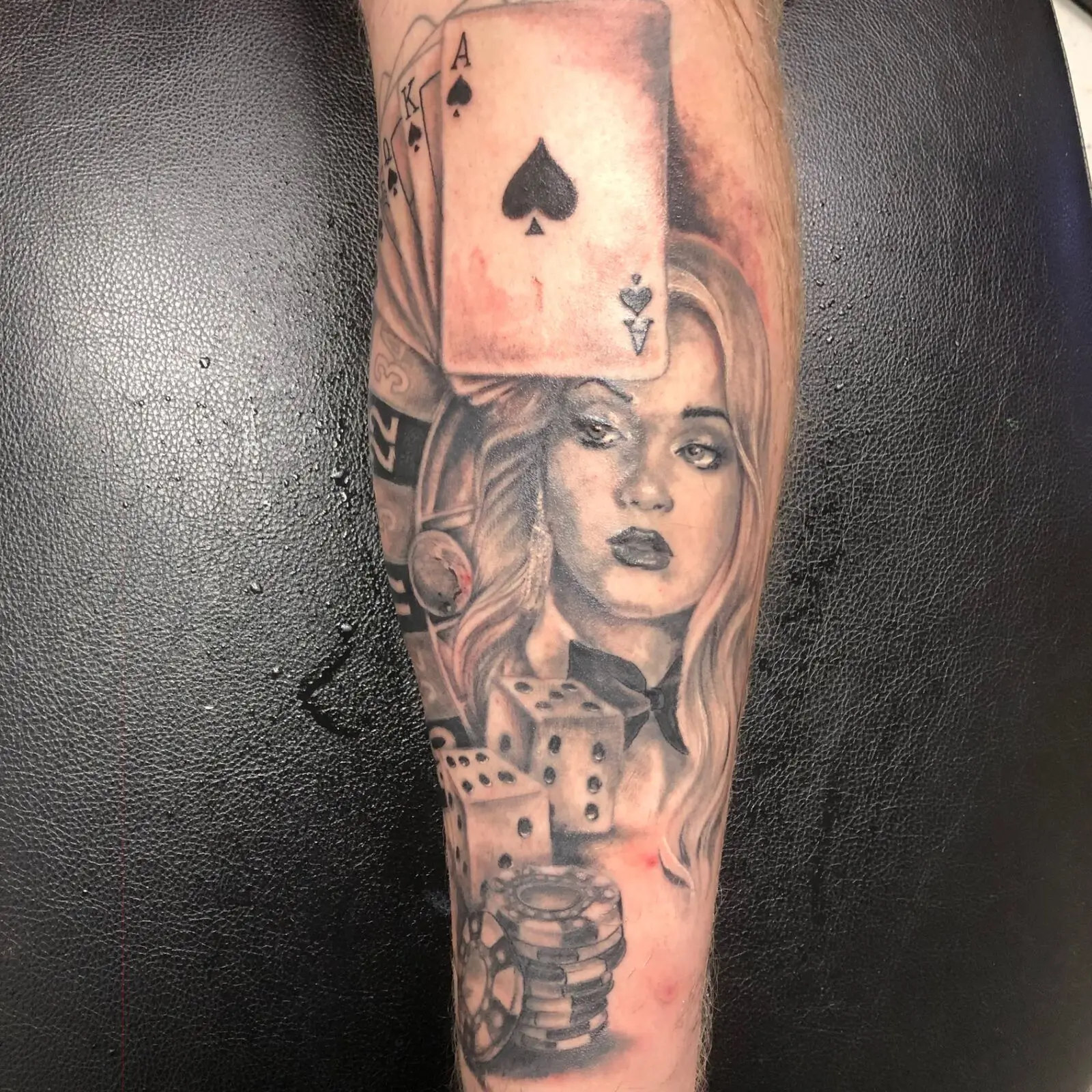 Black and grey gambling-themed portrait tattoo with ace of spades, dice, chips and woman portrait
