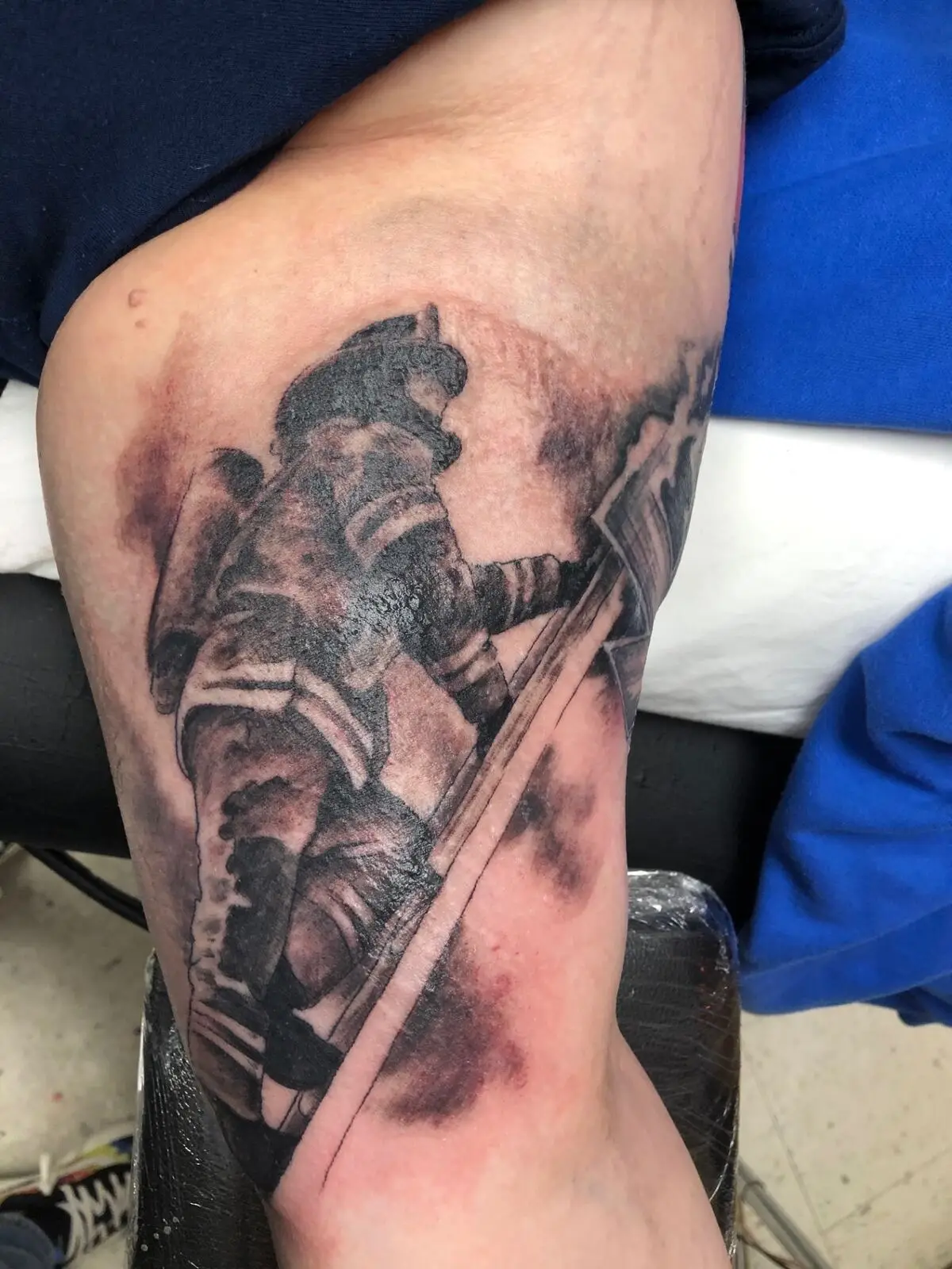 Black and grey firefighter tattoo in action with axe and smoke effects