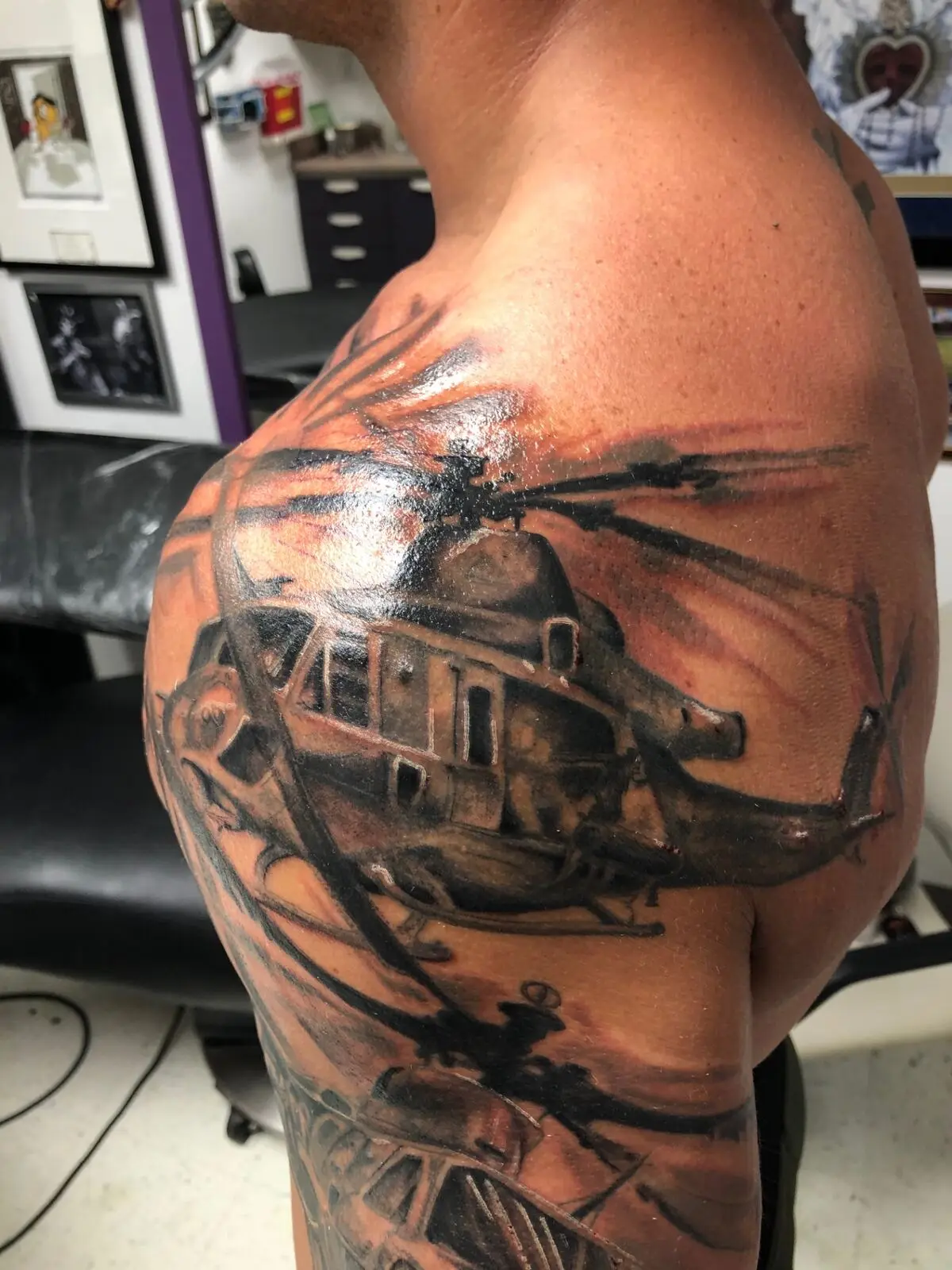 Black and grey helicopter shoulder tattoo with rotor blur and layered aircraft silhouettes