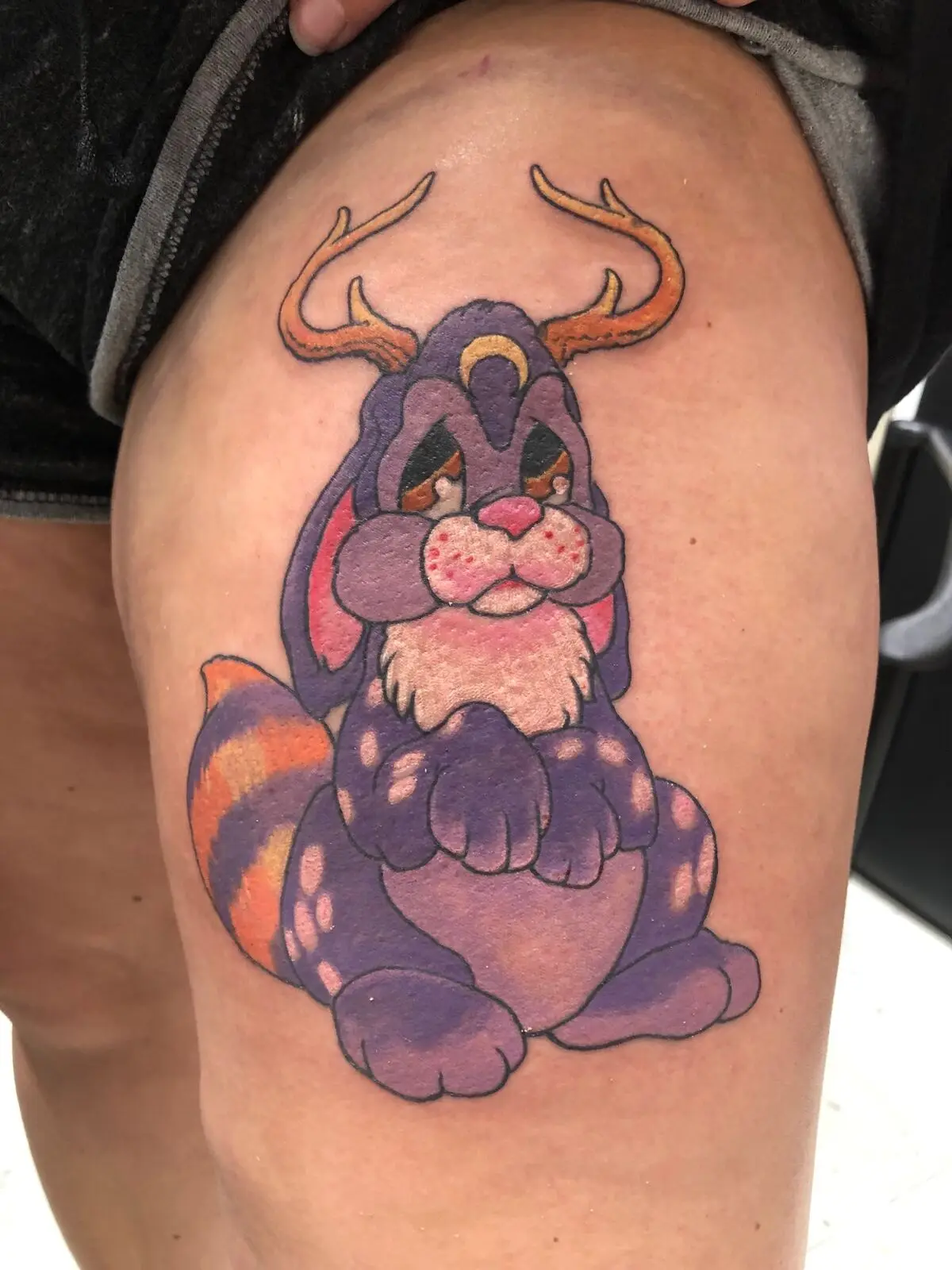 Purple cartoon forest critter tattoo with antlers and orange striped tail