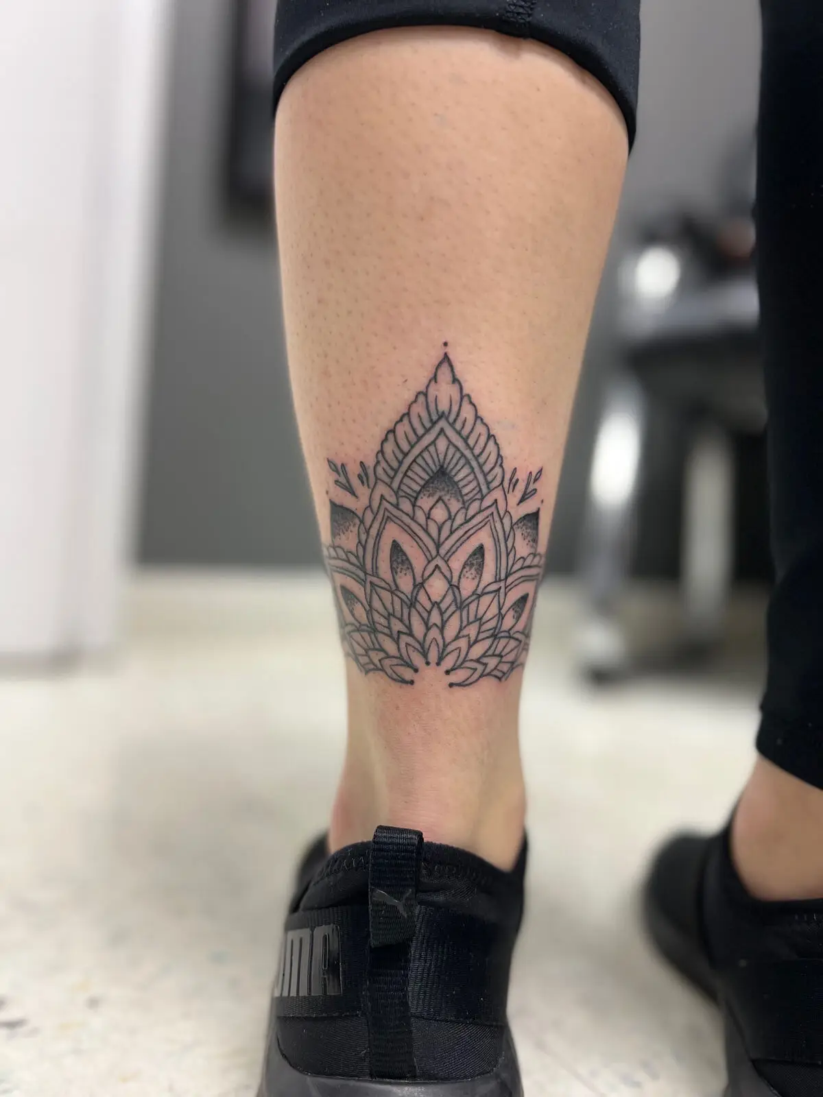 Dotwork and fine line lotus mandala tattoo on the front of the shin, by Carly