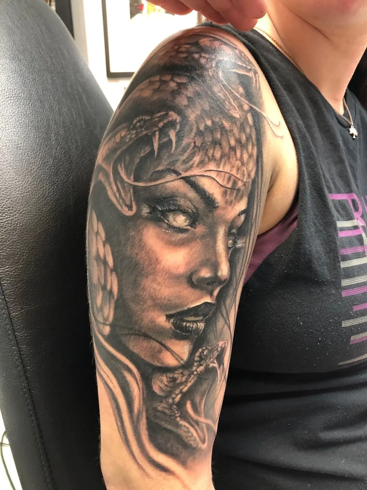 Black and grey Medusa portrait with viper and fangs on the upper arm