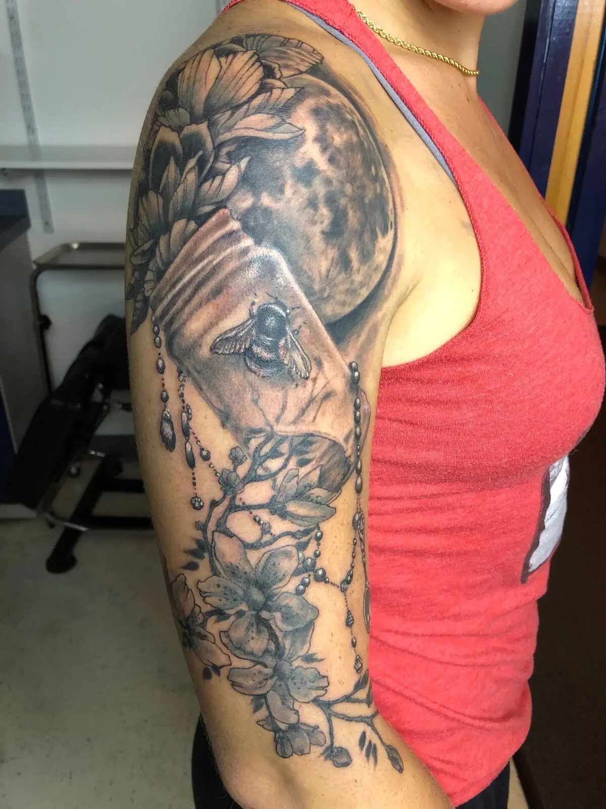 Black and grey moon, lotus and bee half sleeve tattoo with hanging jewels