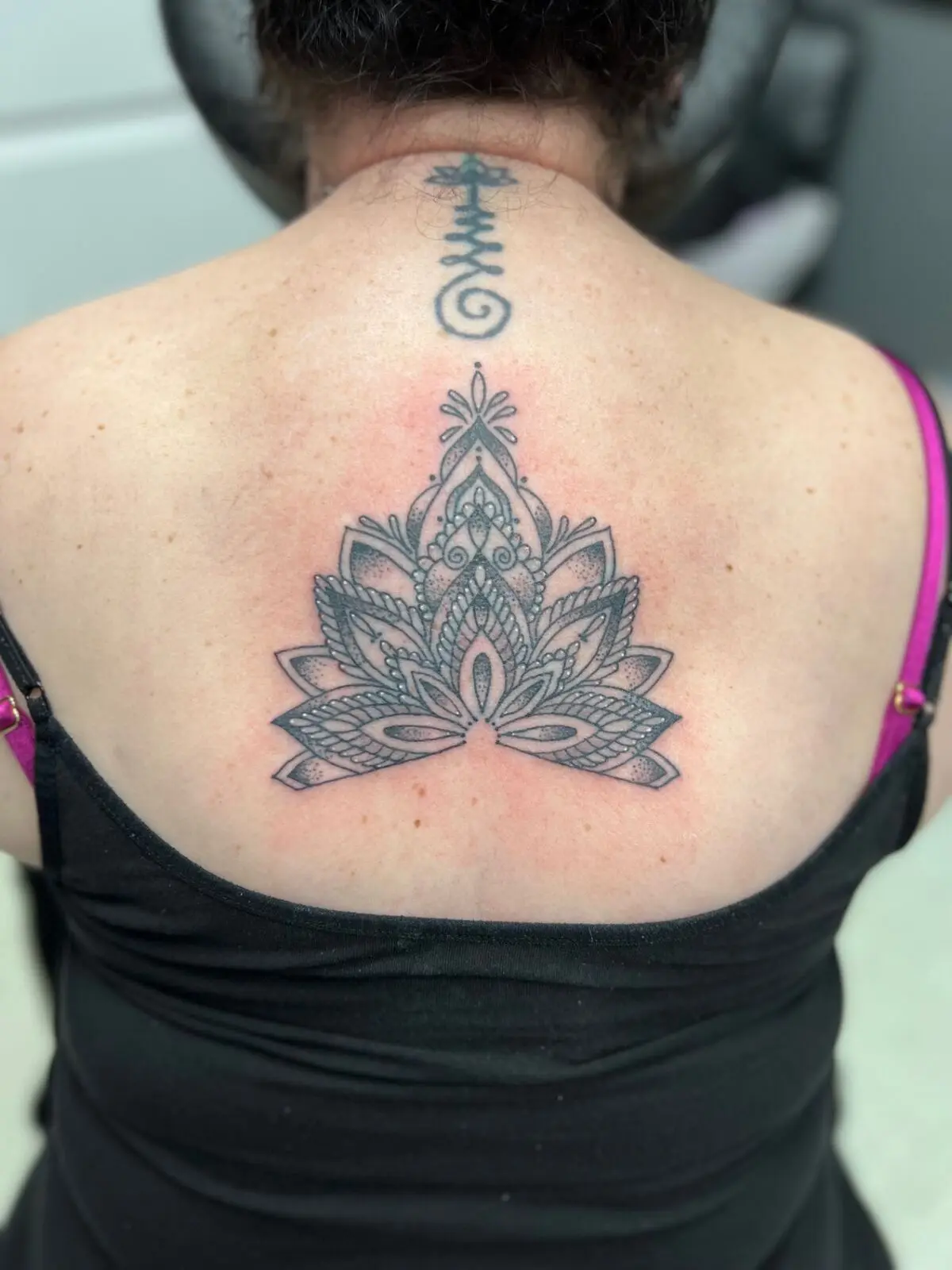 Ornamental dotwork lotus mandala tattoo centered on the upper back, by Carly