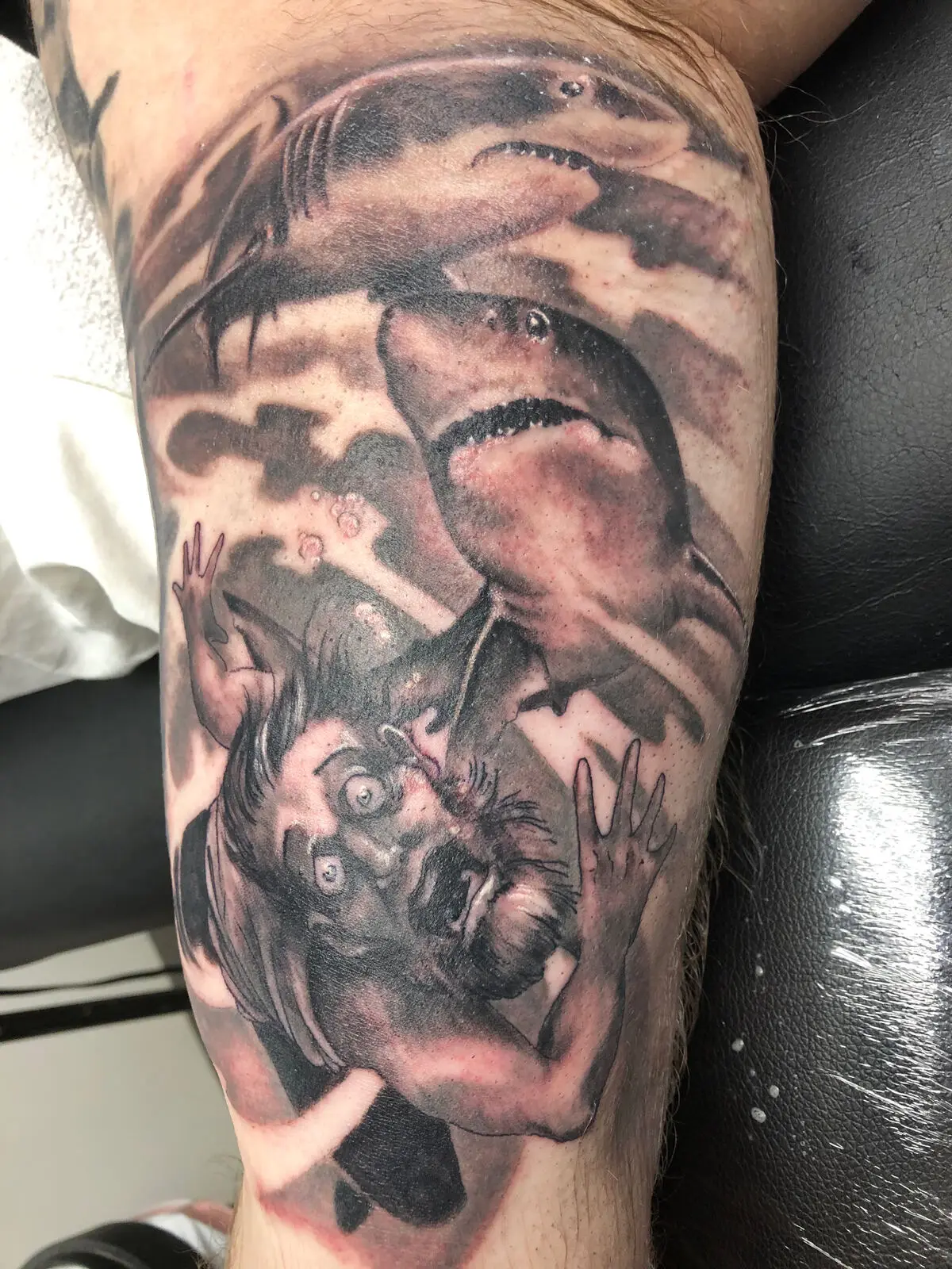 Black and grey shark attack tattoo with diver and bubbles on calf