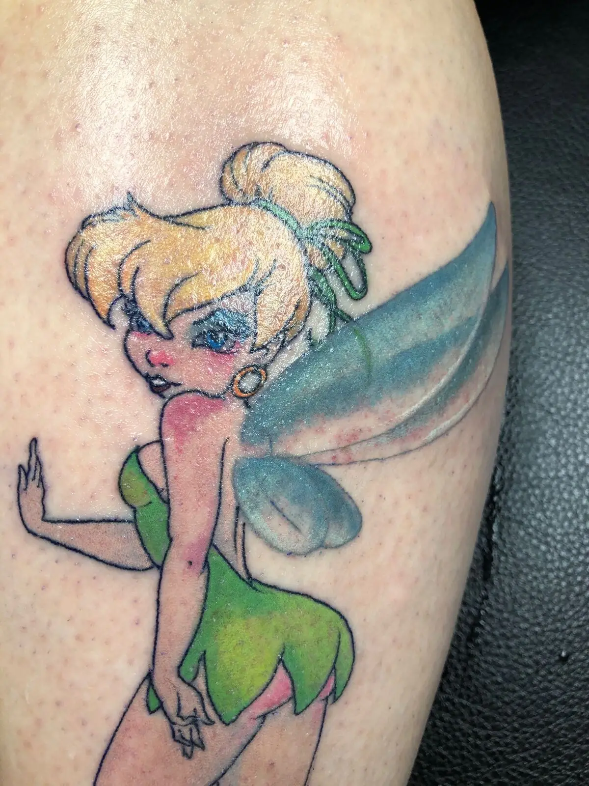 Color illustrative Tinkerbell tattoo on upper arm